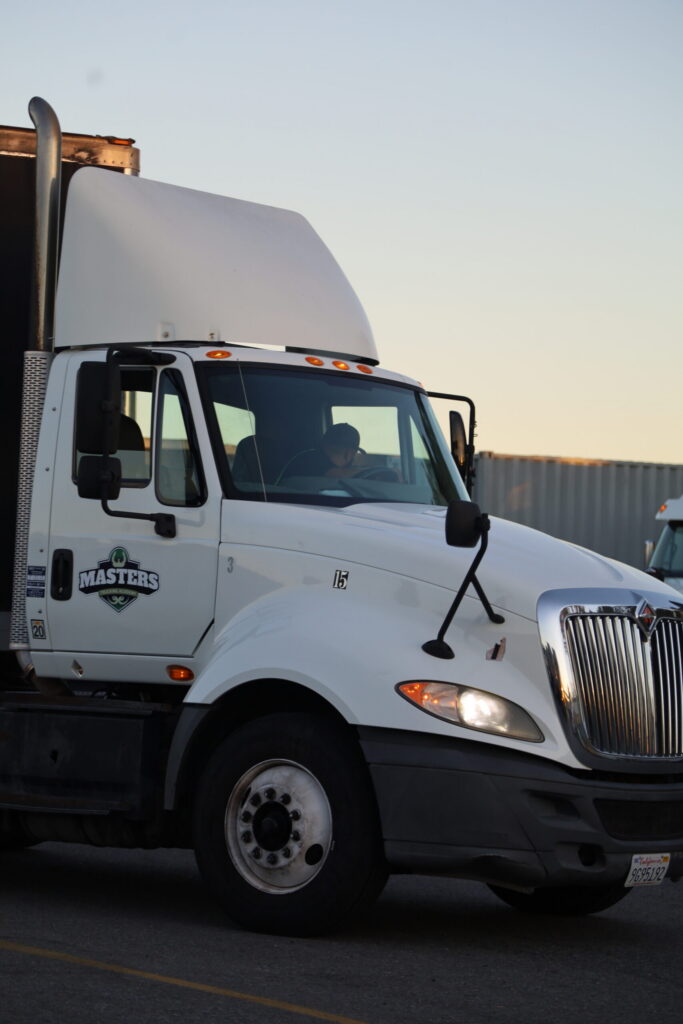 White box truck parked outside a commercial trucking facility.