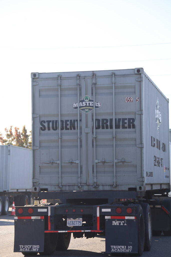 Commercial trailer displaying a student driver sign at a trucking facility.
